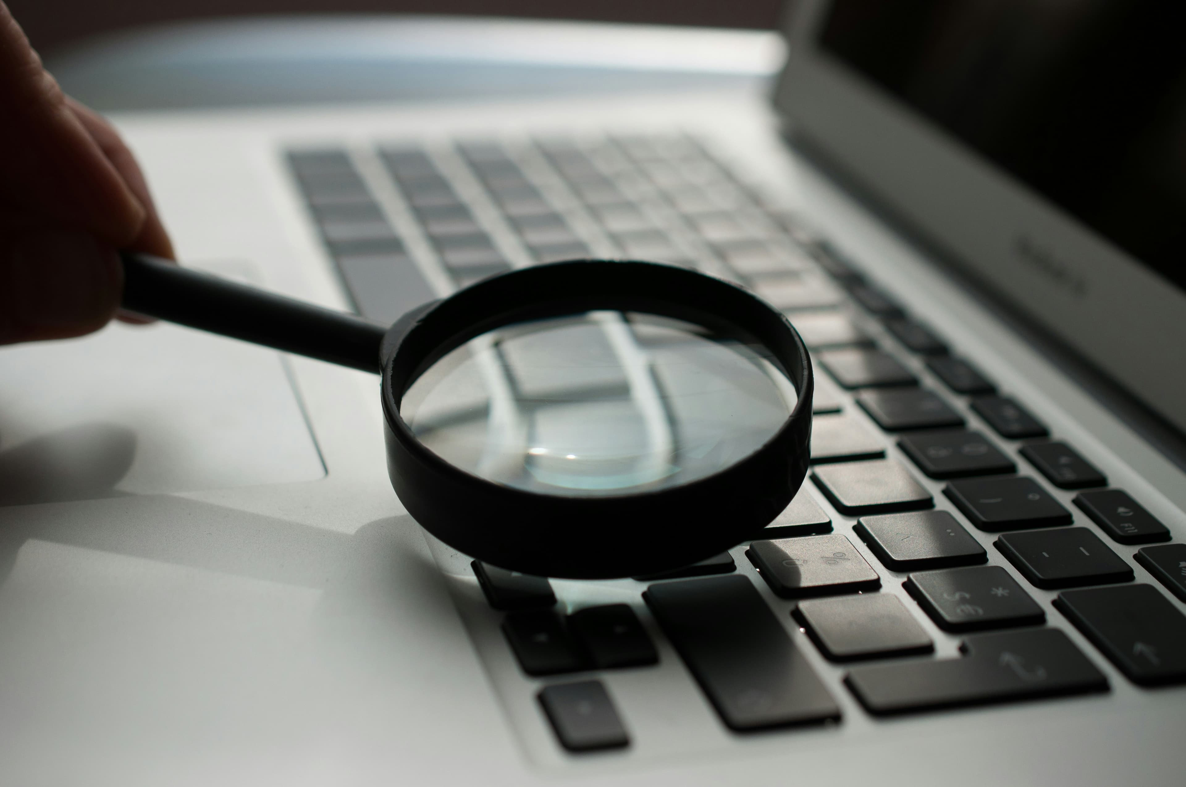 A black magnifying glass over a laptop keyboard