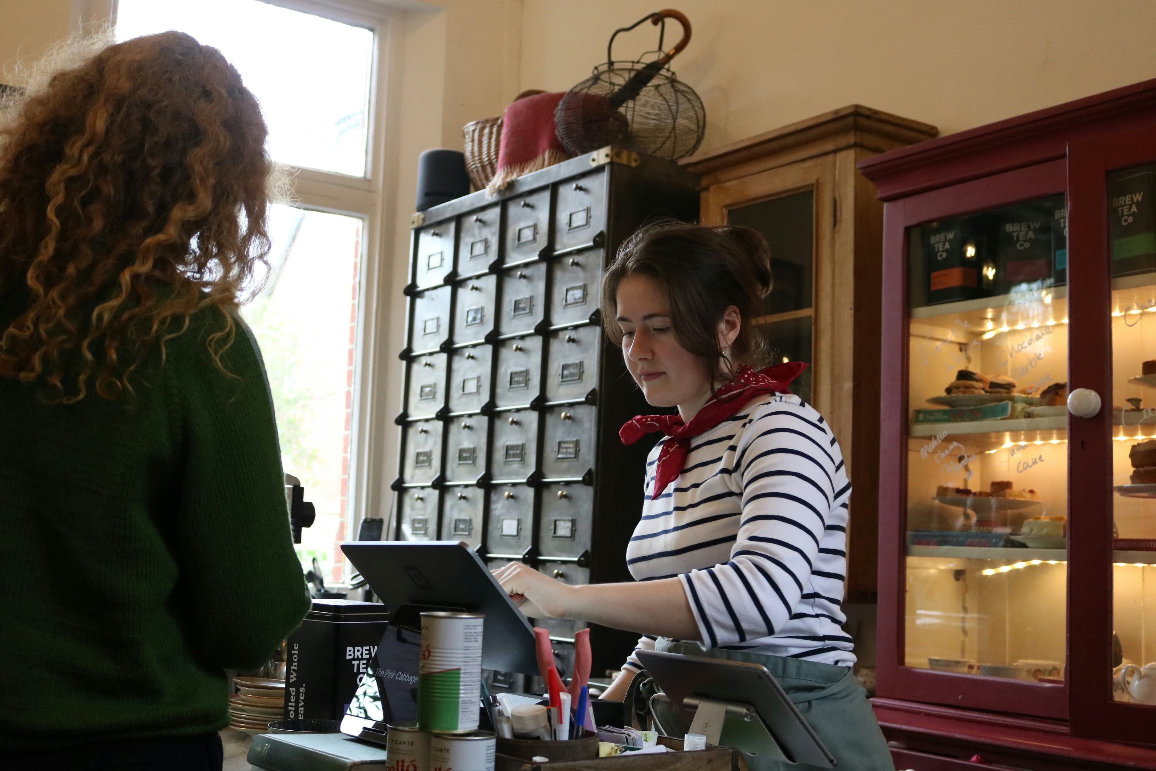 A cashier entering an order at a shop counter while a customer stands in front