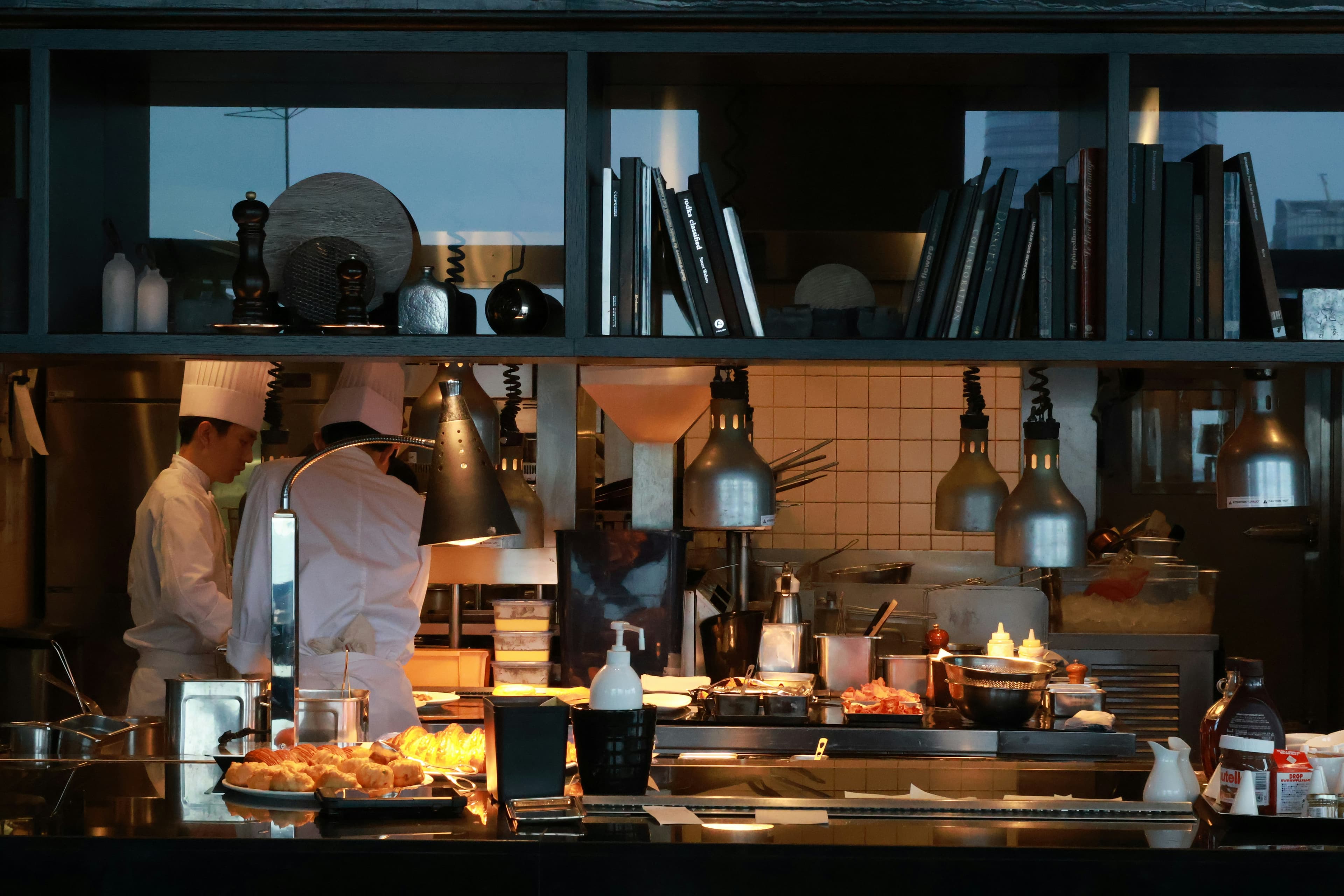 Two chefs in white uniforms cooking at a busy restaurant kitchen line